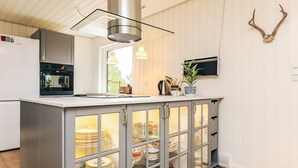 A kitchen with a central island, a stove, and a sink. - 4 Star Holiday Home in Pandrup (Pandrup)