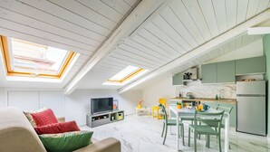 A modern living room with a sofa, TV, and dining area with chairs and a table. - Sloping Roof in the center of Naples (Napoli)