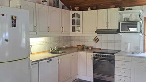 Una cucina compatta con mobili bianchi, un fornello, un lavandino e un forno a microonde.