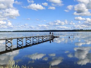 A wooden pier extending into calm water with a clear sky and distant land. - 6 Person Holiday Home in Storvorde (Storvorde)