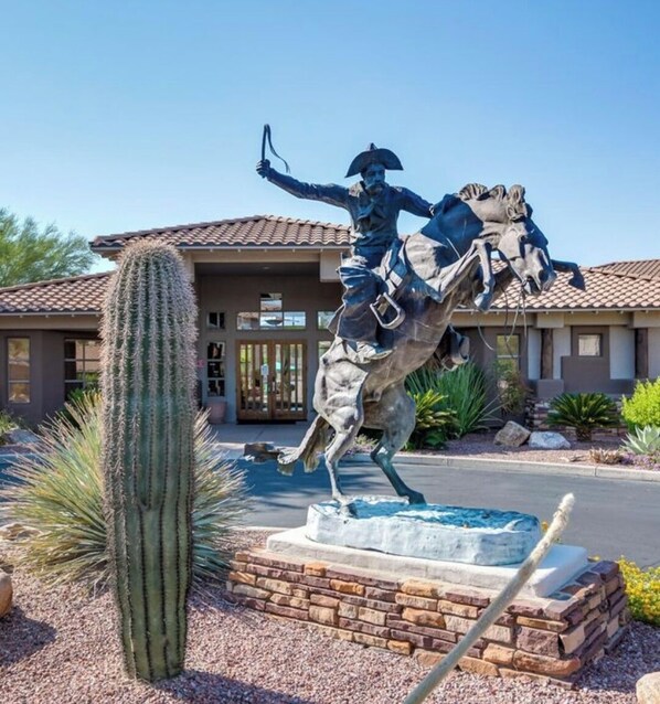 A statue of a mounted figure in front of a house with a tiled roof and a cactus in the foreground. - Cozy Desert Nest! (Oro Valley)