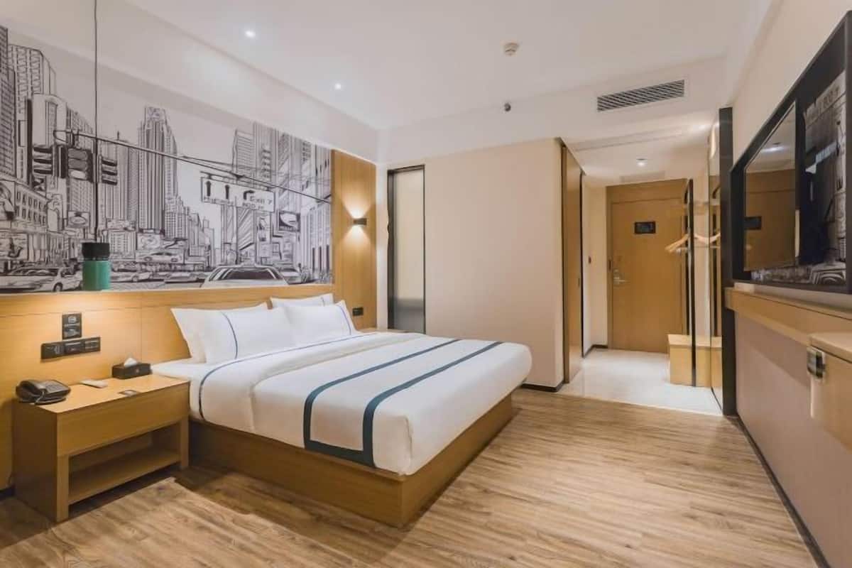Quarto de hotel com cama, mesa de cabeceira, um mural na parede e um espelho.