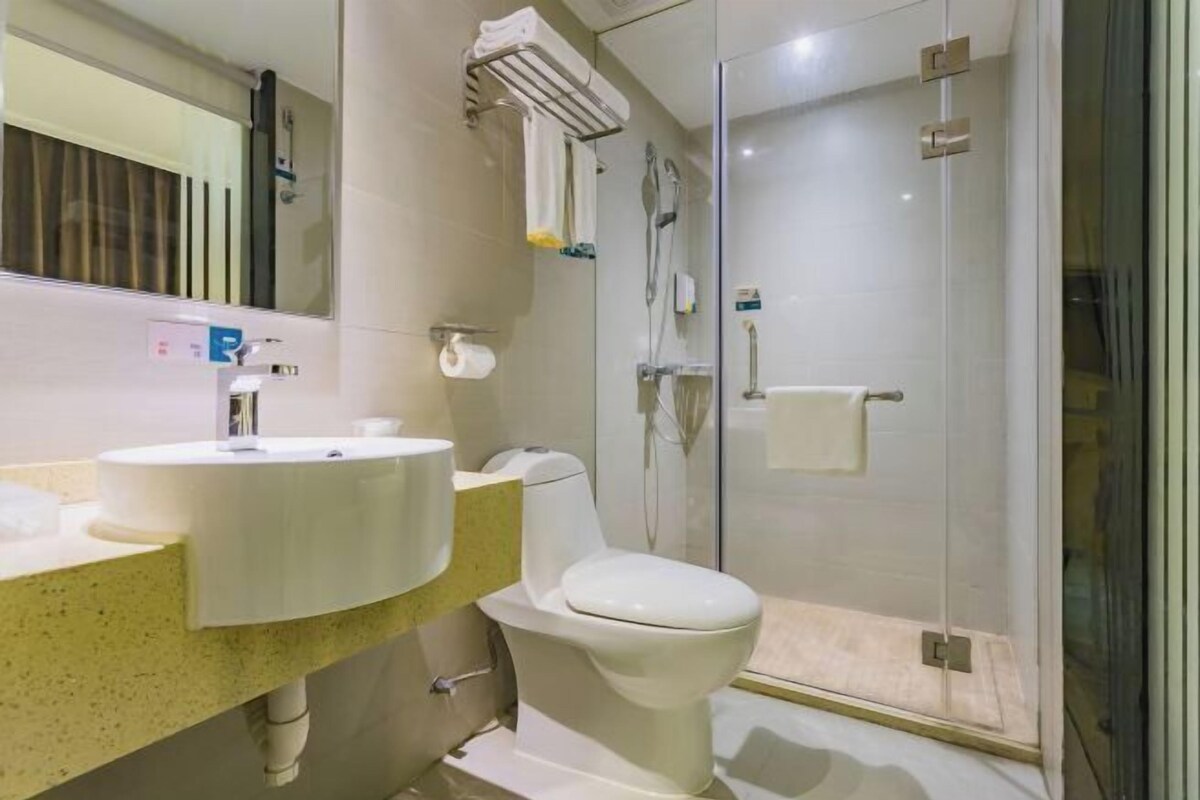 A modern bathroom with a glass shower enclosure, a sink with a mirror, and a toilet.