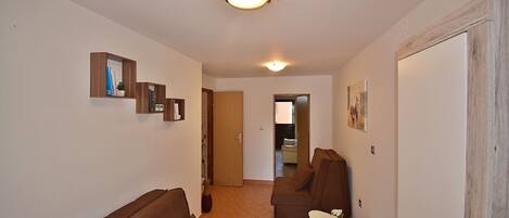 A living room with a sofa, a small table, and a door leading to another room.