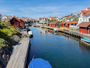 A narrow waterway with boats docked on the left, surrounded by traditional red and white houses with red roofs. - 4 Star Holiday Home in Grundsund (Grundsund)