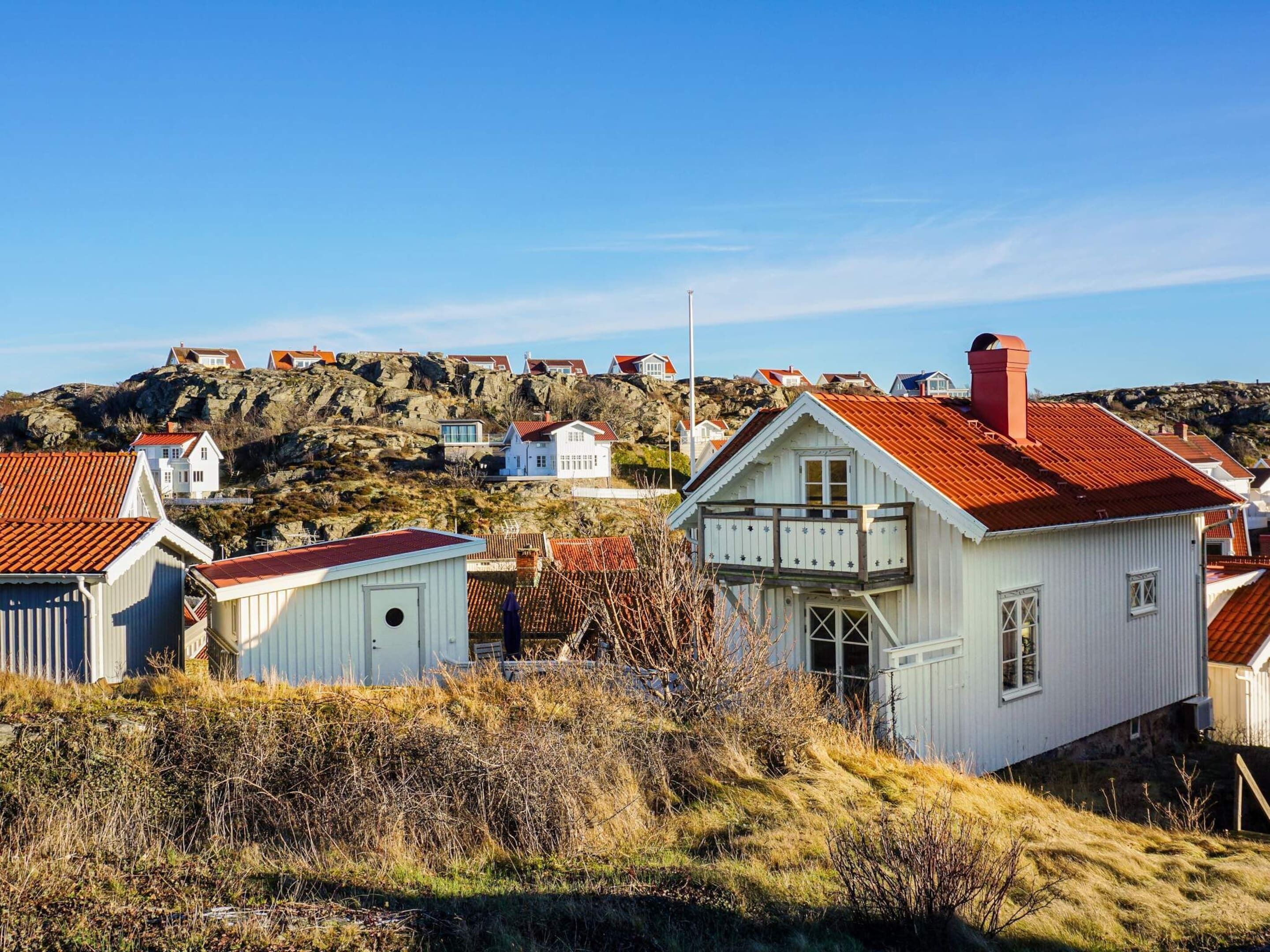 Un village côtier aux maisons blanches et aux toits rouges, entouré d’un paysage rocheux.