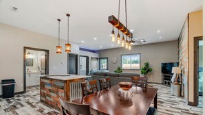 A modern kitchen with a central island, dining area with a wooden table and chairs, and a living area with a sofa and television. - Raccoon Lake Retreat (Rockville)