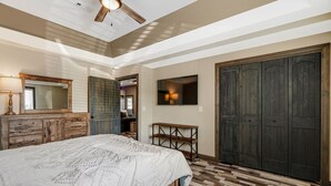 A bedroom with a large bed, wooden dresser, a TV, and a wardrobe. - Raccoon Lake Retreat (Rockville)