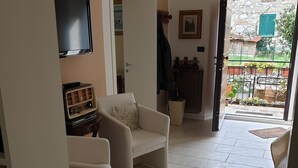 Un salon comprenant un canapé, un téléviseur et une porte donnant sur un espace extérieur.