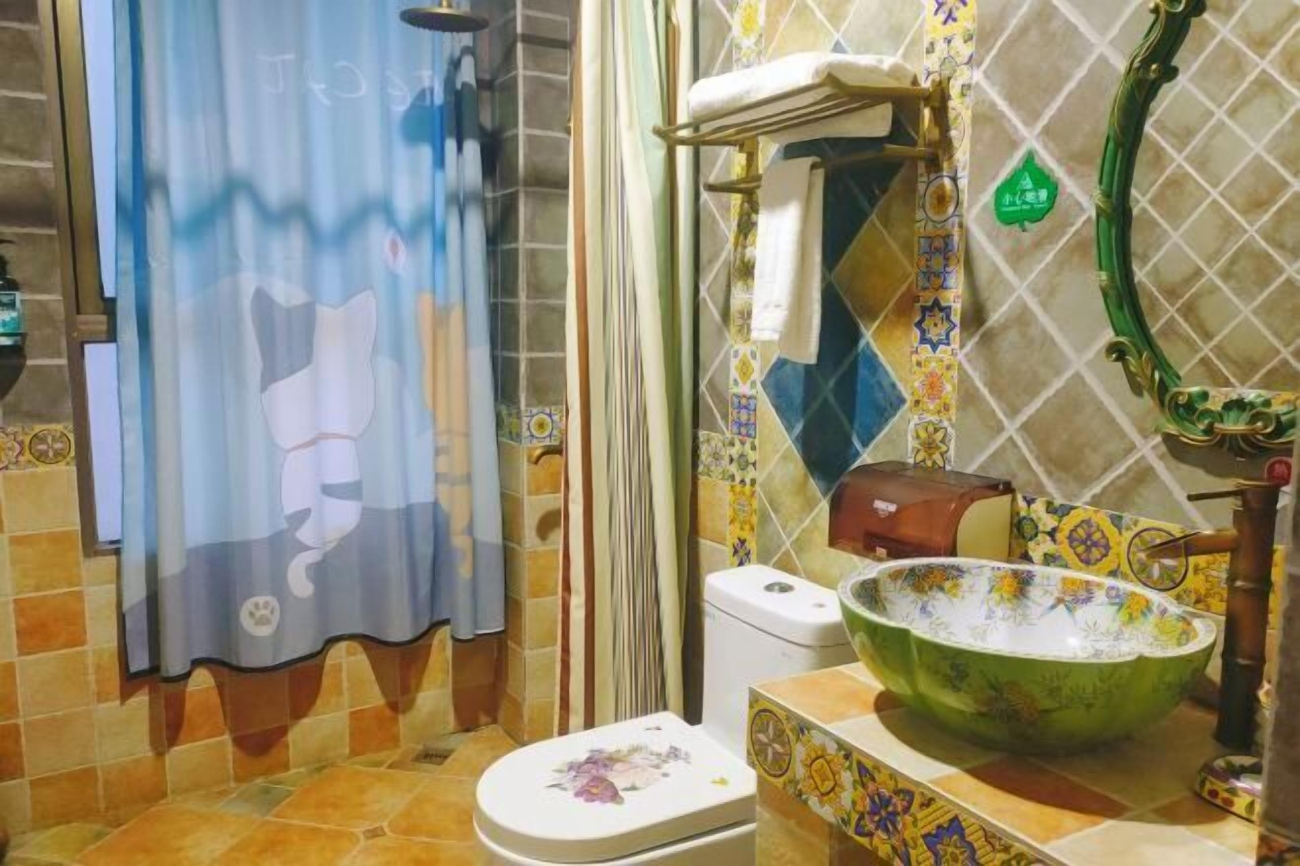 A bathroom with a toilet, a sink with a decorative bowl, a shower curtain, and a towel rack.