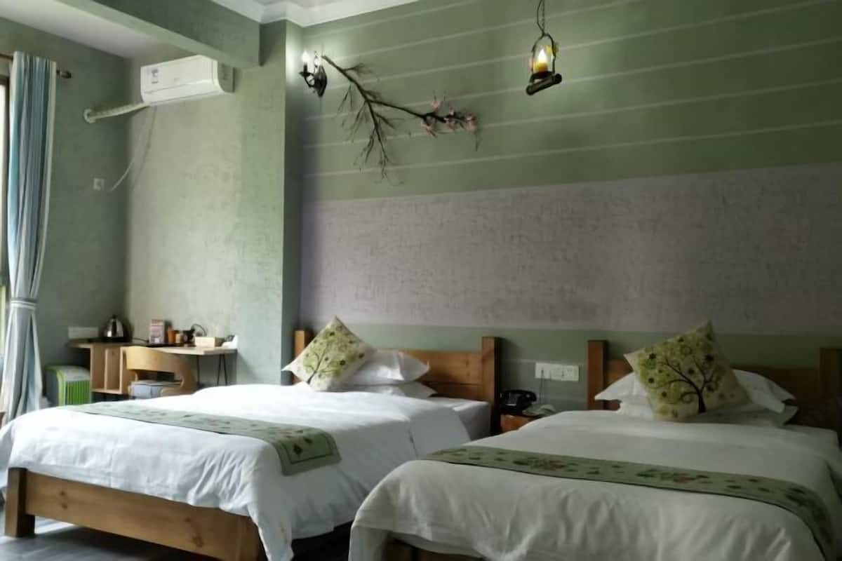 A room with two beds, a desk, and a wall-mounted air conditioner.