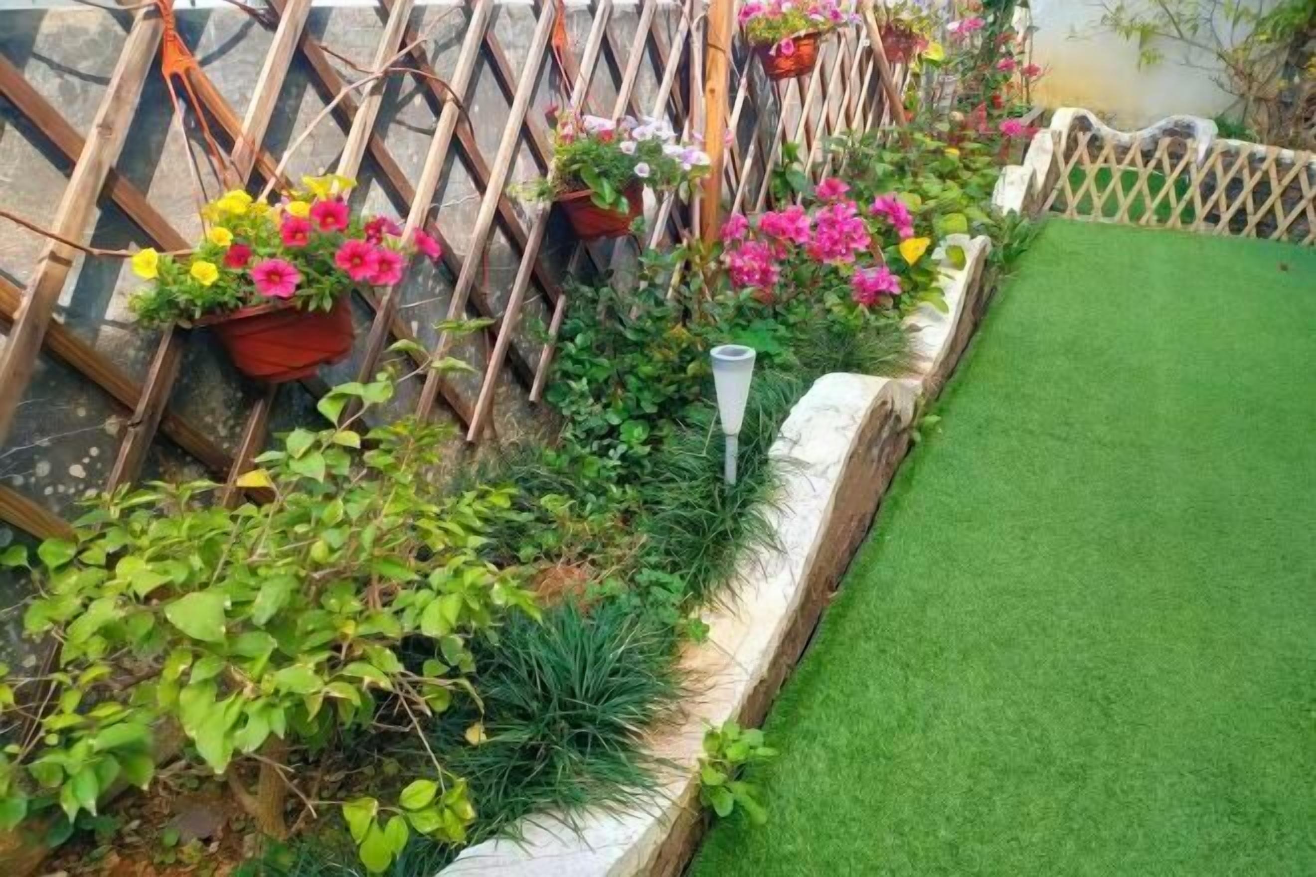 A garden with a wooden fence, potted plants, and a grassy area.
