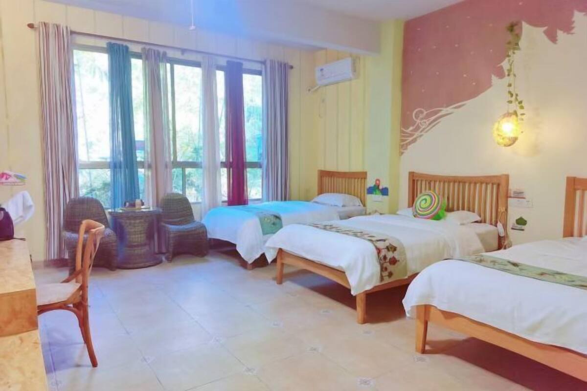 A hotel room with three beds, a dining table, and chairs.