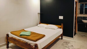 A bedroom with a wooden bed, a green towel, and a white pillow. - Nature Valley Gokarna  (Kumta)