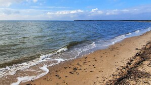 A beach with waves, a clear sky, and distant land. - 6 Person Holiday Home in Spottrup (Spøttrup)