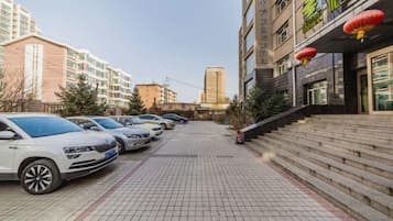 A parking area with multiple cars, a staircase leading to a building, and a clear sky.