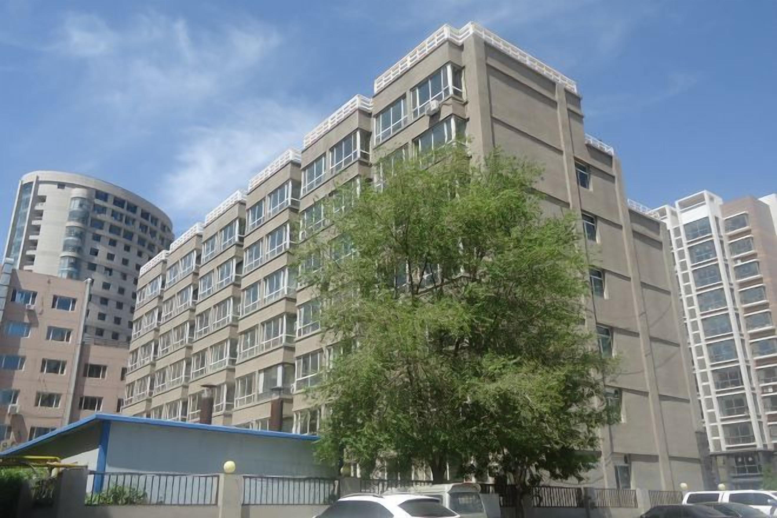 A multi-story building with a flat facade, large windows, and a tree in front.