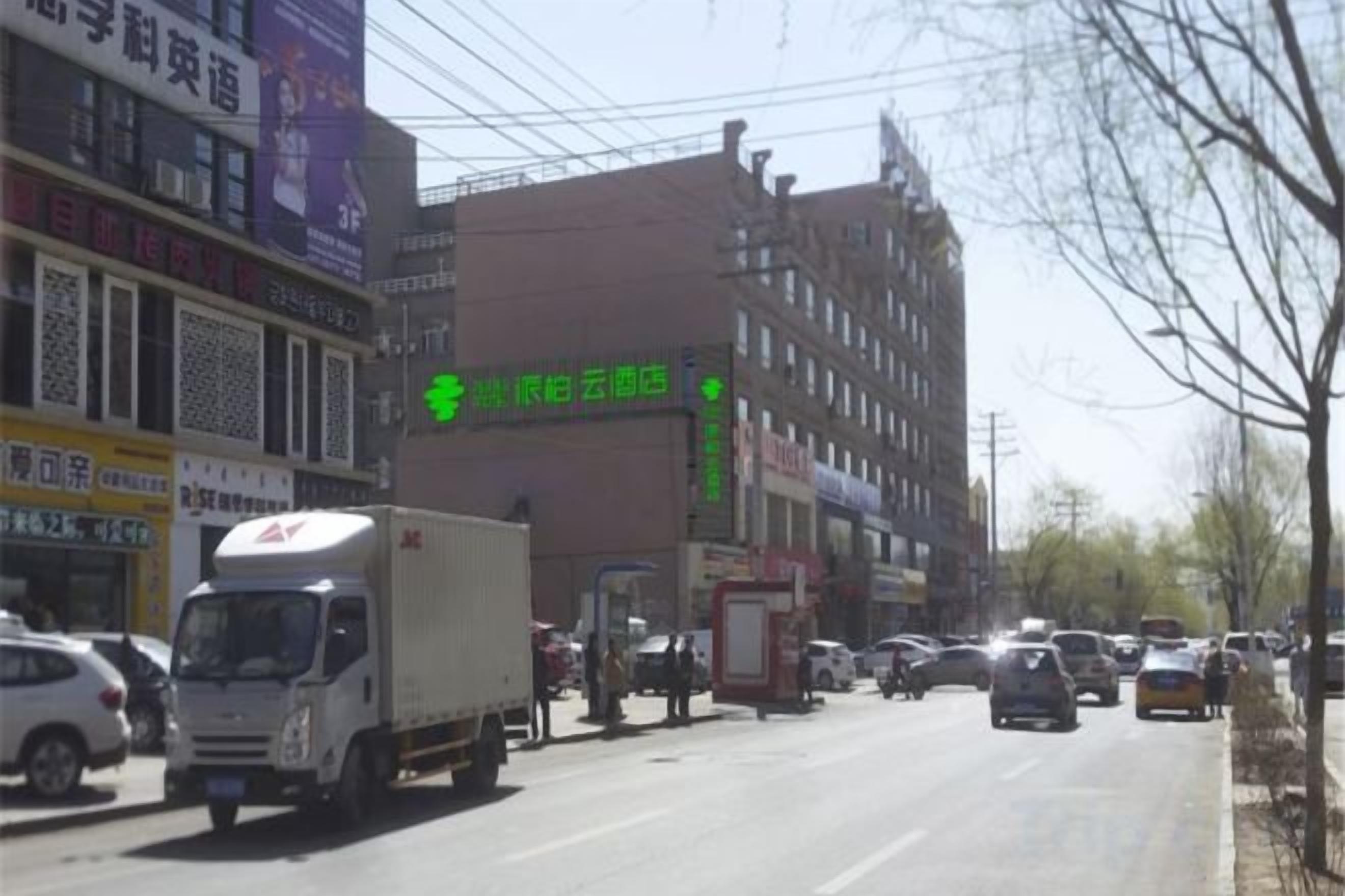A street with multiple vehicles, including a white truck and several cars, passing by.