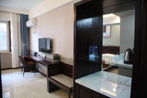 A hotel room with a desk, chair, television, and a minibar. - Homeinn Pebble (Hohhot Chuangye Road International Mongolian Hospital) (Hohhot)