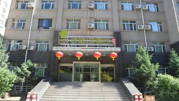 A multi-story building with a central entrance, air conditioning units on the facade, and a staircase leading to the entrance.