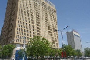 A tall building with a grid-like facade, surrounded by trees and street lamps. - Homeinn Pebble (Hohhot Chuangye Road International Mongolian Hospital) (Hohhot)
