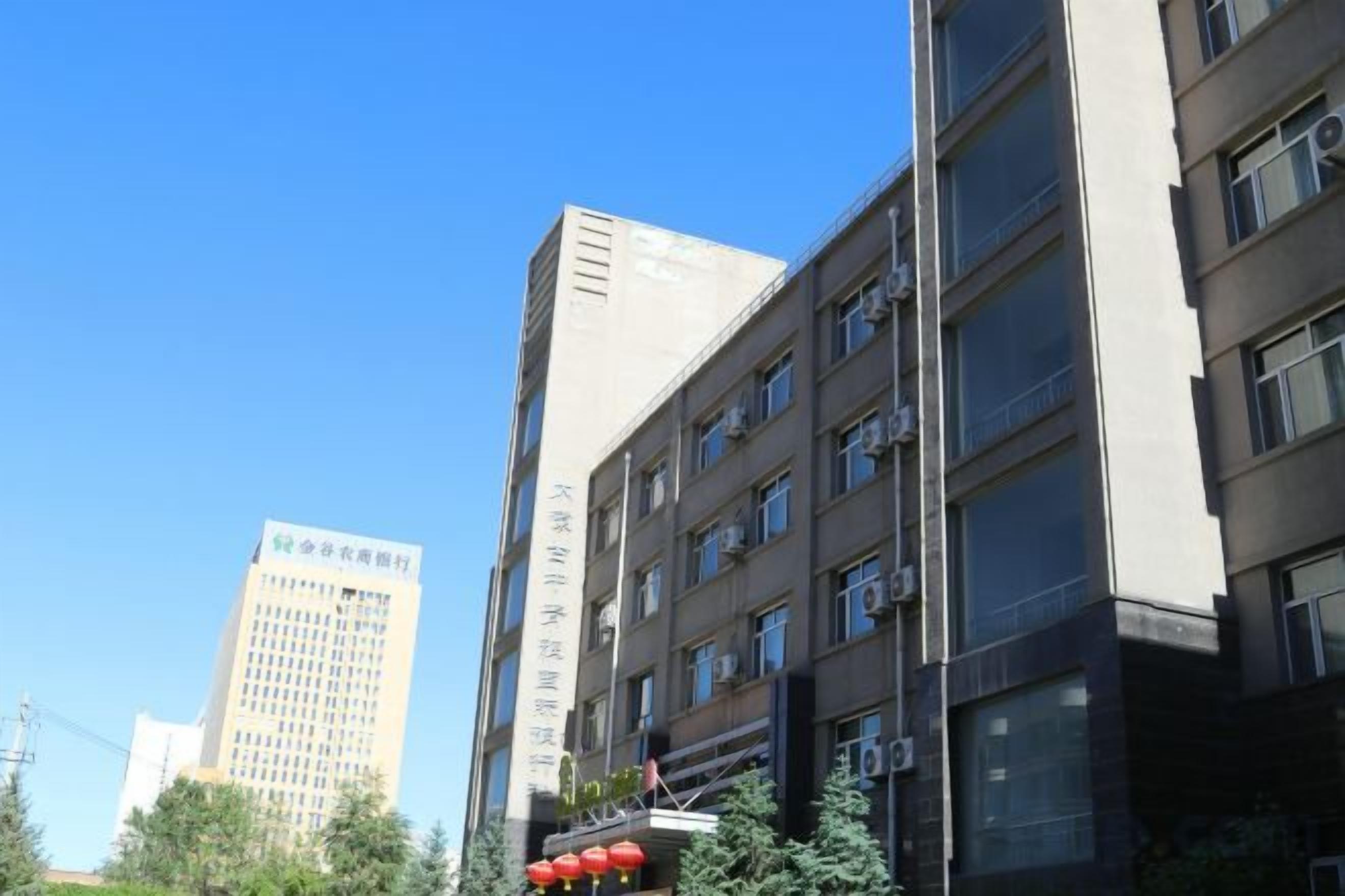 Un edificio de varios pisos con fachada plana, ventanas amplias y una entrada visible con rampa.