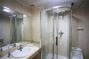 Une salle de bain avec une douche à parois de verre, un lavabo avec un miroir et des toilettes.