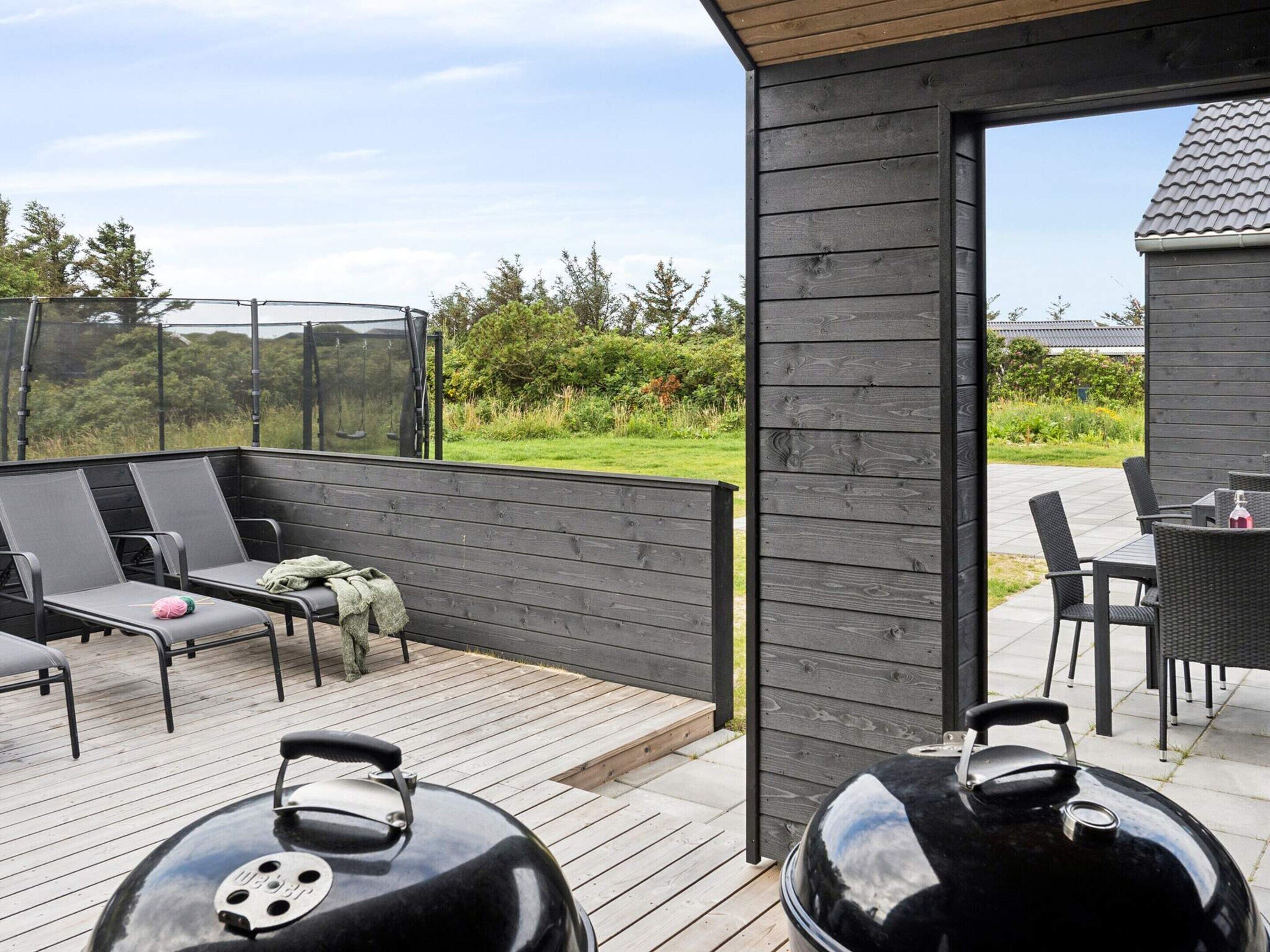 Een terras buiten met zitplaatsen, een barbecue en uitzicht op het omliggende groen.
