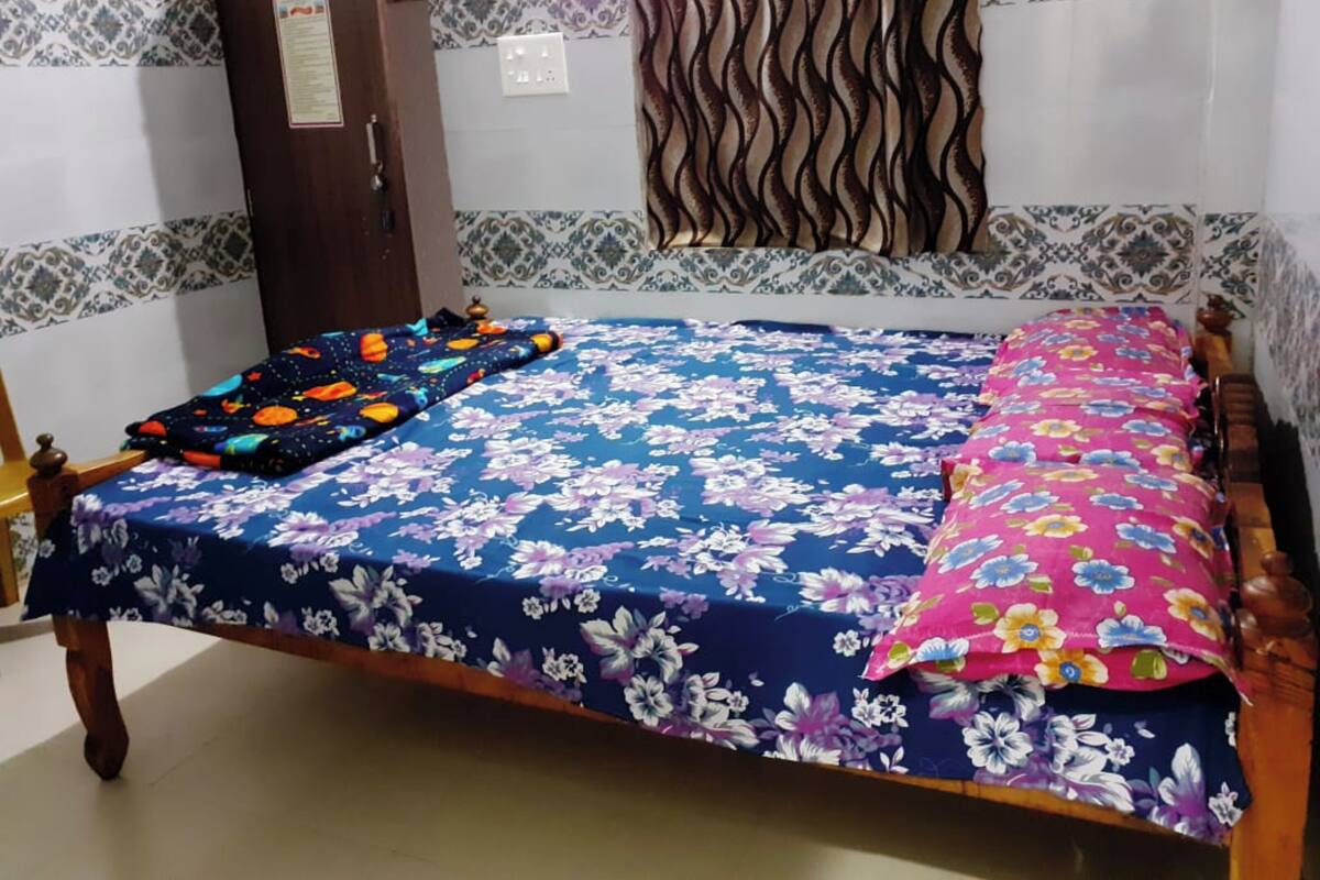Un dormitorio con una cama cubierta de ropa de cama floral, un armario de madera y papel tapiz estampado.