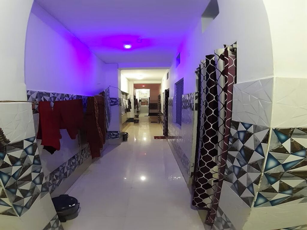 Un pasillo con baldosas estampadas, una prenda roja colgada y una cortina con diseño.