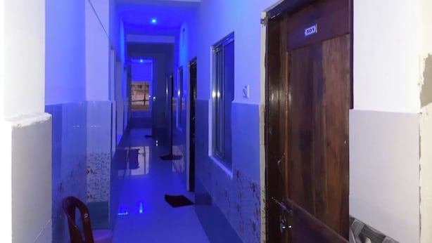 Un pasillo con una puerta de madera con la etiqueta '501' y una silla al frente.