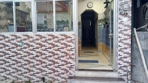 Fachada de edificio con azulejos, una puerta visible y un reloj en la pared.