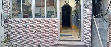 Fachada de edificio con azulejos, una puerta visible y un reloj en la pared.