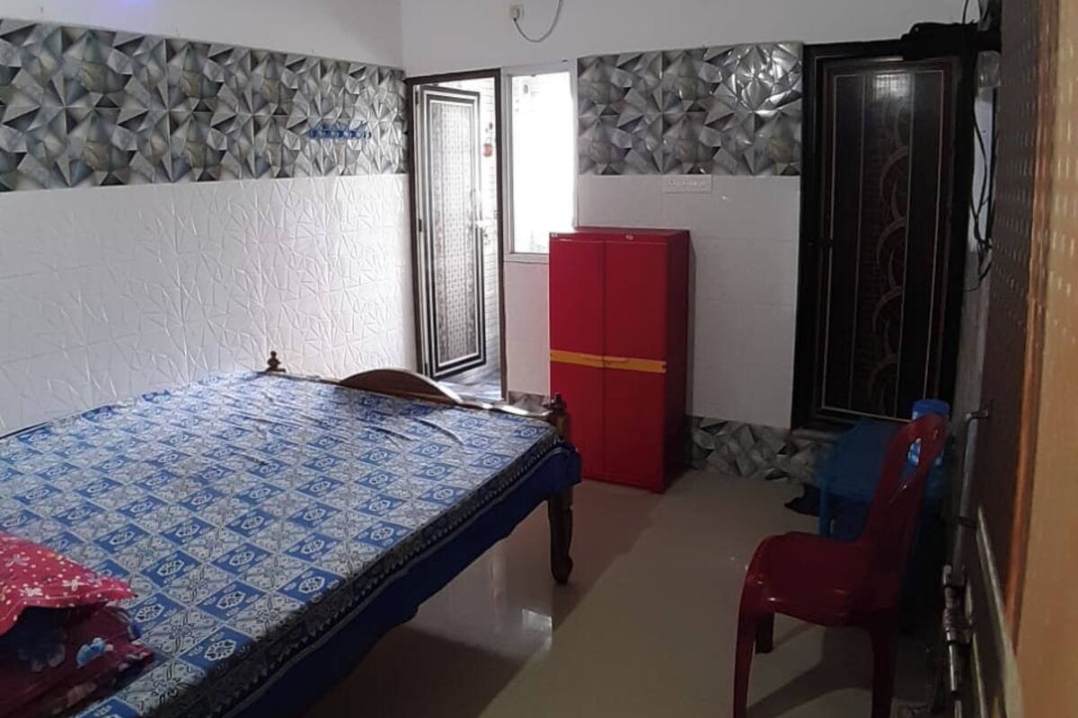 Un dormitorio con cama, un armario rojo, ventilador de techo y ventana con vistas.
