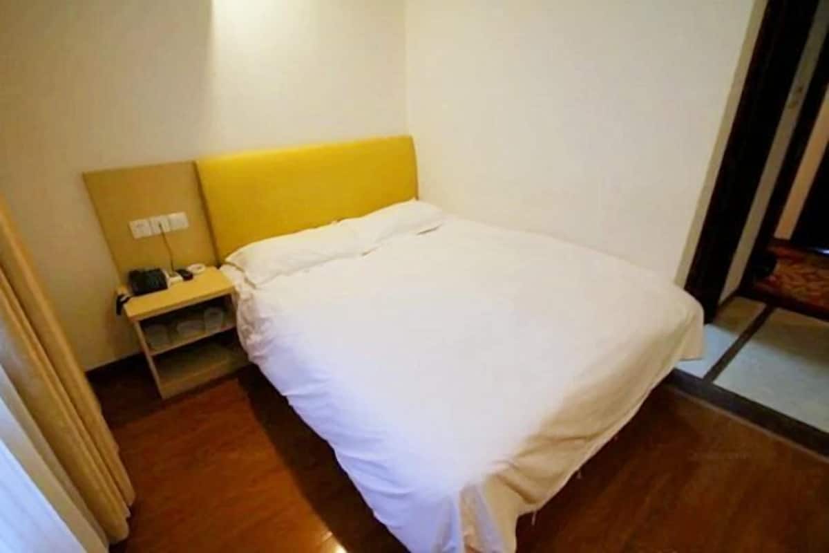 A hotel room with a bed, a nightstand, and a mirror.