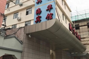 A building with a curved overhang and a sign with red characters. - Xinyu Hotel (Shanghai Sichuan North Road Subway Station) (Shanghai)