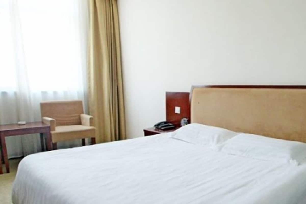 A hotel room with a bed, a chair, a bedside table, and a nightstand.