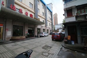 A street view with a building that has a sign in a foreign language, a parked car, and a sidewalk.