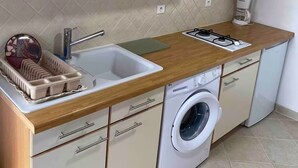 A compact kitchen with a sink, a coffee maker, a washing machine, and a dish rack. - Typical little house in the village of Piana (Piana)