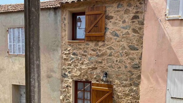 A stone building with a wooden door and window shutters. - Typical little house in the village of Piana (Piana)
