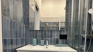 Une salle de bain moderne avec un meuble-lavabo blanc, un miroir et une cabine de douche en verre.