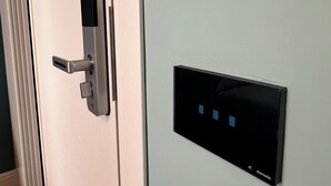 Une porte dotée d’une serrure moderne et d’un panneau de commande avec quatre boutons rétroéclairés.