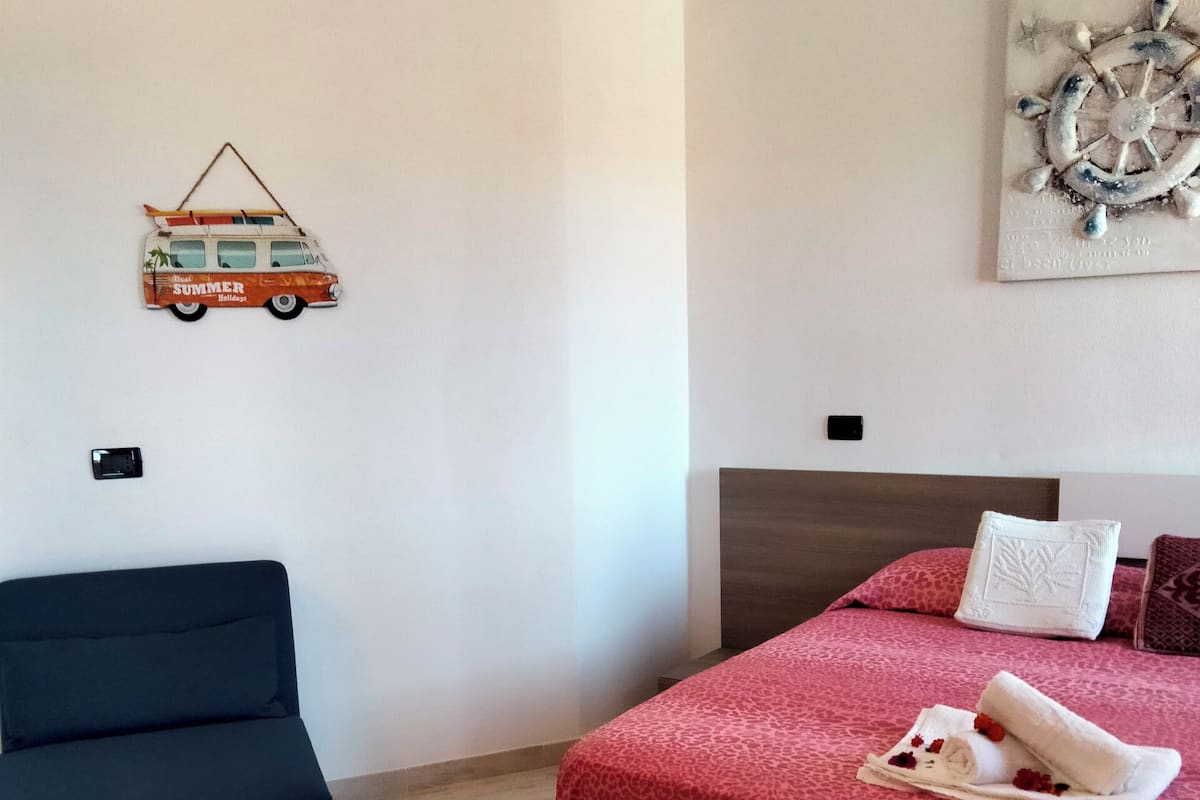 A bedroom with a bed, a sofa, a wall-mounted artwork, and a small decorative item.