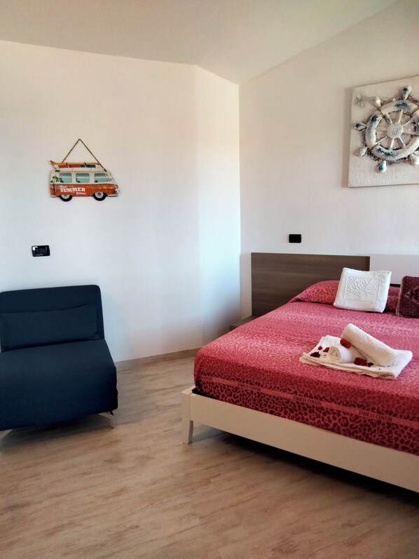 Un dormitorio con cama, sofá, una obra de arte en la pared y un objeto decorativo.