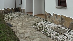 A building with a tiled roof, white walls, and a stone pathway leading to a door. - My Tiffany Rooms (Tanaunella)