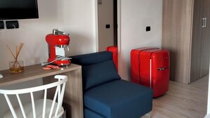 A modern room with a wooden desk, a blue sofa, a red refrigerator, and a TV mounted on the wall. - My Tiffany Rooms (Tanaunella)