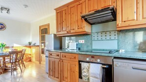 A kitchen with wooden cabinets, a stainless steel refrigerator, a microwave, and a dishwasher. - The perfect location to explore the Highlands. (Nairn)