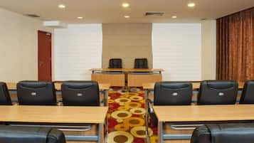 A conference room with a long table, multiple chairs, and a carpet with a circular pattern.
