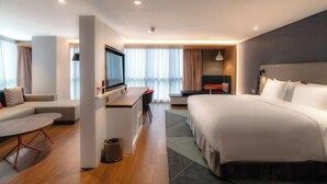 Une chambre d’hôtel moderne équipée d’un grand lit, d’un bureau, d’un canapé et d’une télévision.