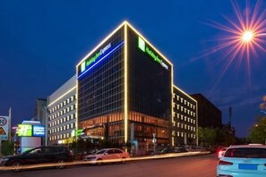 Ein modernes Hotelgebäude mit einer auffälligen Beschilderung, mehreren Etagen und einer gut beleuchteten Fassade.